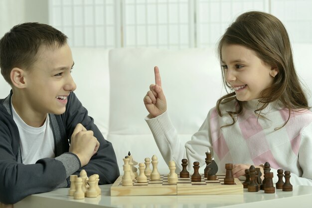 Menino e menina jogando xadrez em casa. Crianças jogando xadrez