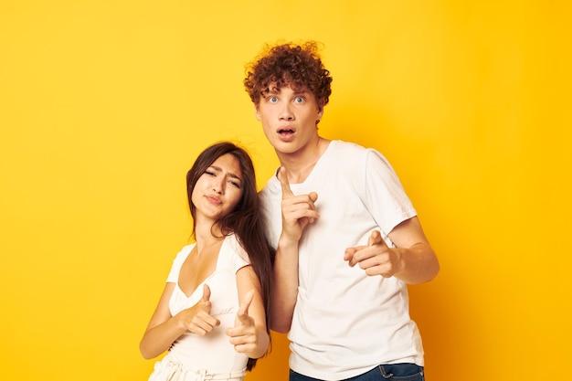 Menino e menina lado a lado em camisetas brancas posando fundo amarelo inalterado