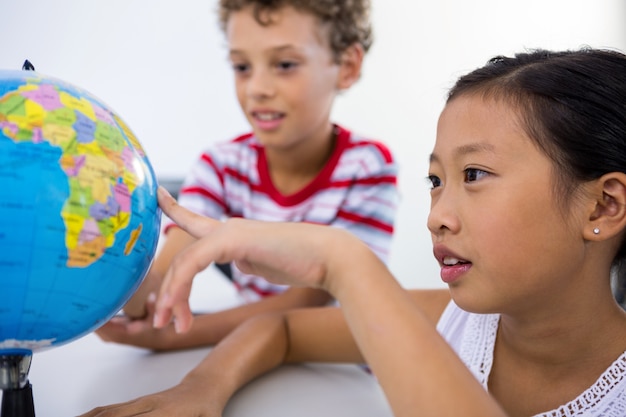 Foto menino e menina olhando glob na sala de aula