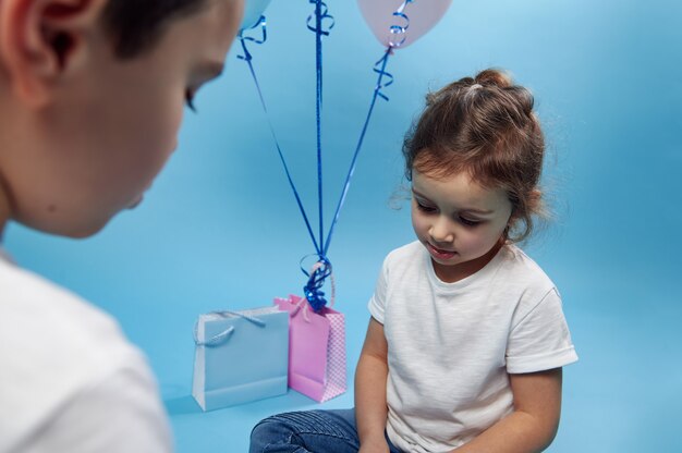 Menino e menina olhando para baixo na superfície azul com espaço de cópia