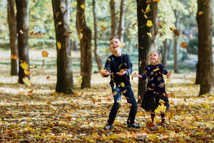 Menino e menina pegam folhas que caem no parque outono