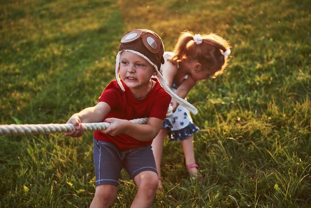 Foto menino e menina puxando uma corda e jogando cabo de guerra no parque