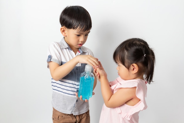 Menino e menina usando gel anti-séptico de álcool para limpar as mãos. Desinfecção por coronavírus