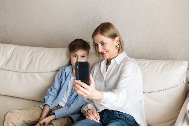 Menino e mulher tirando uma selfie ao telefone enquanto sorriem