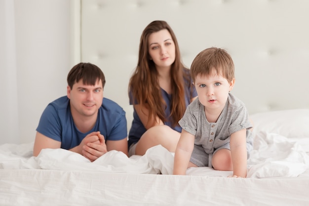 Menino e os pais na cama dos pais de pijama