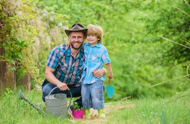 Menino e pai na natureza com regador jardim primavera pai ensinando plantas a cuidar do filho pequeno ajudante no jardim plantando flores plantando plantas mudas frescas cuide das plantas