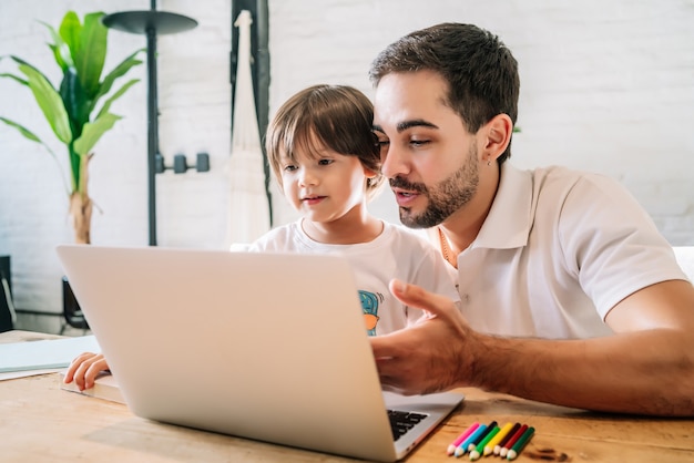 Menino e seu pai usando um laptop juntos enquanto ficavam em casa. novo estilo de vida normal. conceito monoparental.