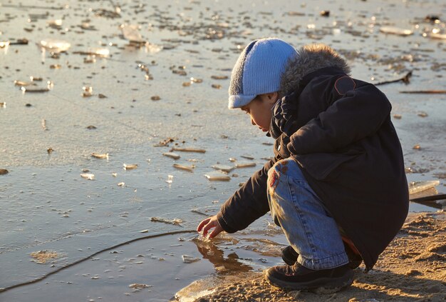 Foto menino e uma menina brincando perto do rio em dia ensolarado de inverno.