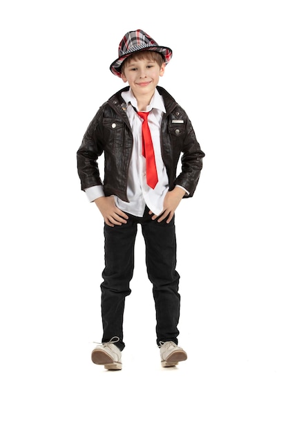 Menino elegante em oito altura em um fundo branco Criança em um chapéu uma jaqueta de couro com um vermelho