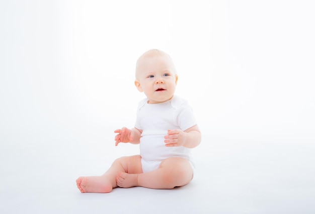 Menino em bodysuit branco sentado em um fundo branco