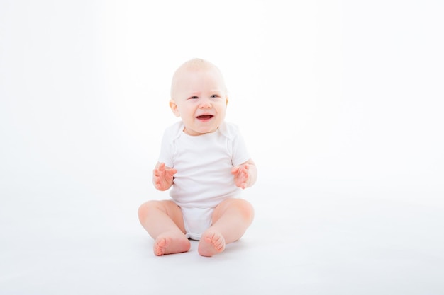 Menino em bodysuit branco sentado em um fundo branco