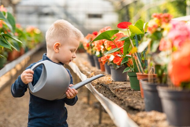 Menino em estufa regando flores