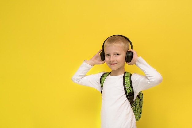 Menino em fones de ouvido com uma mochila em um fundo amarelo com espaço de cópia