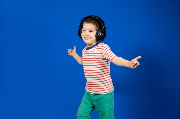 Menino em grandes fones de ouvido pretos aponta os dedos para os lados no lugar para espaço de cópia de texto