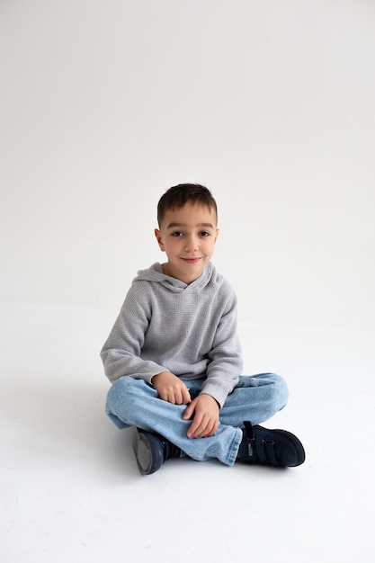 Menino em idade pré-escolar sorrindo e posando em fundo cinza em estúdio fotográfico