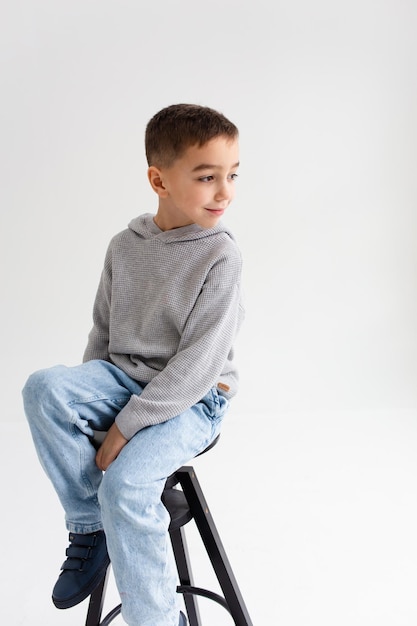 Menino em idade pré-escolar sorrindo e posando em fundo cinza em estúdio fotográfico