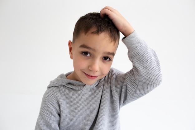 Menino em idade pré-escolar sorrindo e posando em fundo cinza em estúdio fotográfico