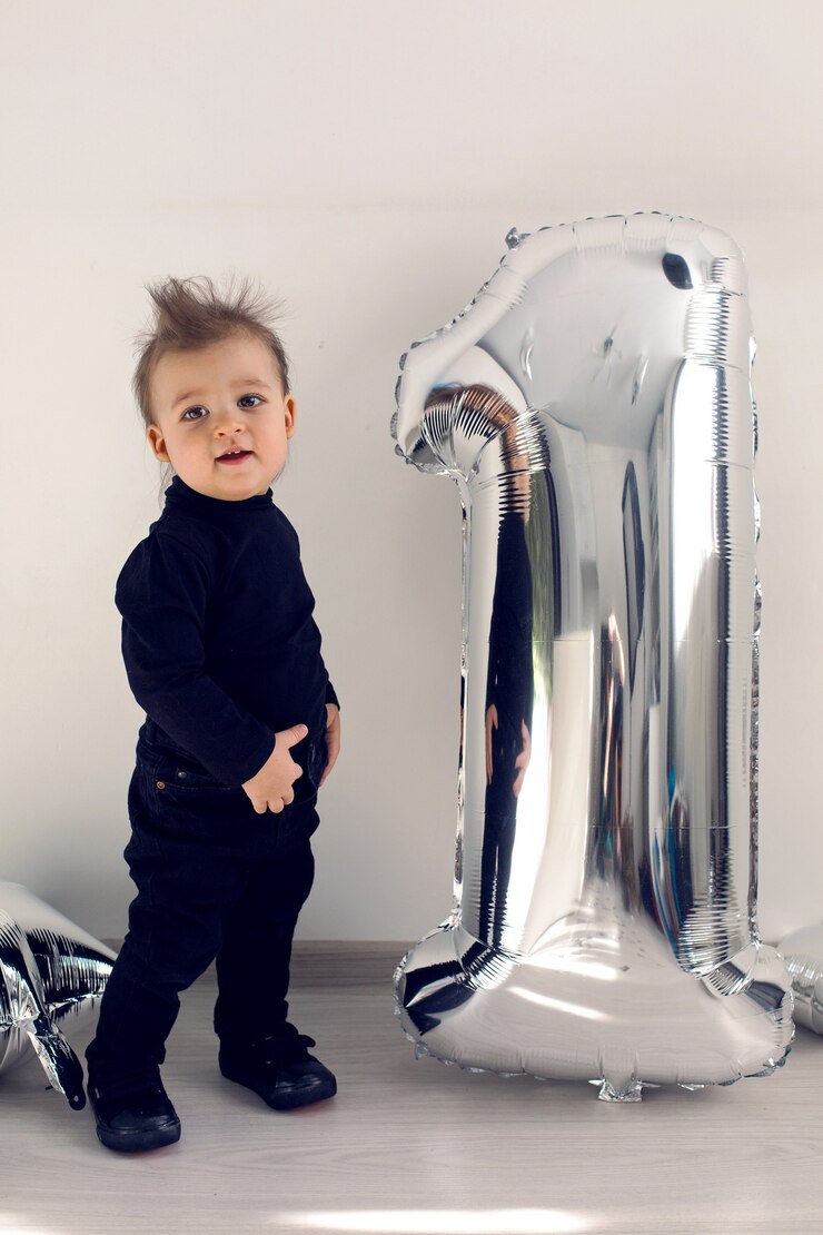 Foto menino em roupas pretas com figura inflável de prata