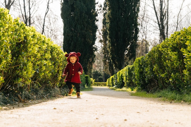 Menino em um belo terno caminhando no parque na primavera sob o sol