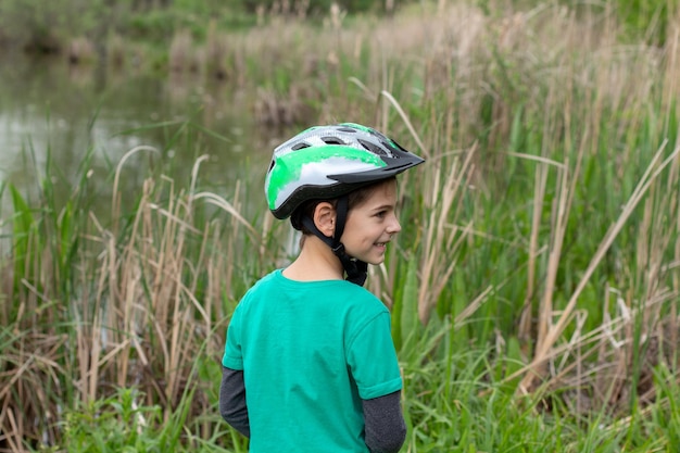 Menino em um capacete de bicicleta ao ar livre no verão