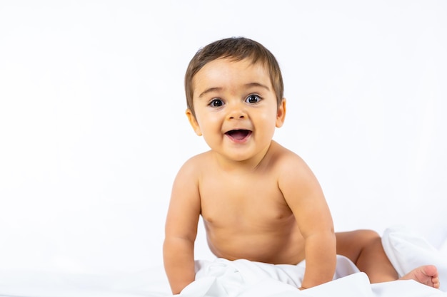 Menino em um estúdio com fundo branco, caucasiano, recém-nascido de oito meses, sentado, olhando para a câmera