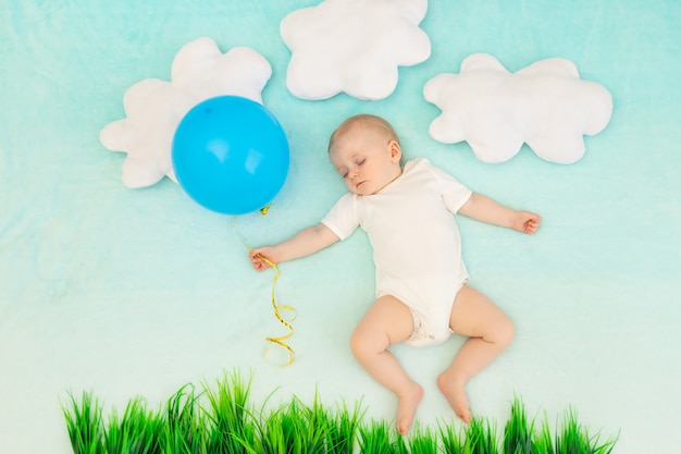 Menino em um fundo azul entre as nuvens com um balão dormindo