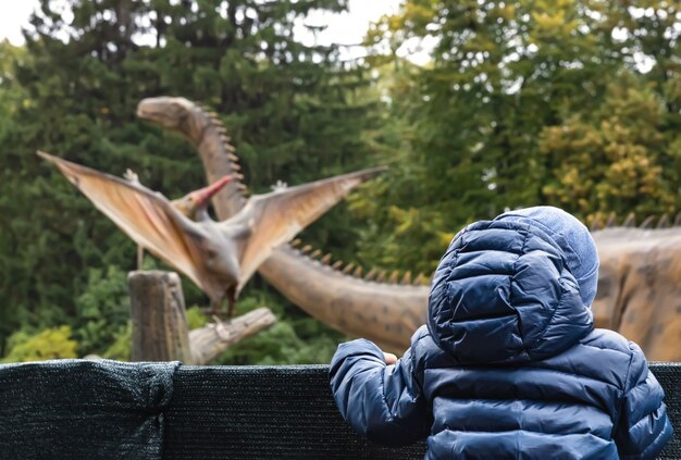 Menino em um parque de dinossauros