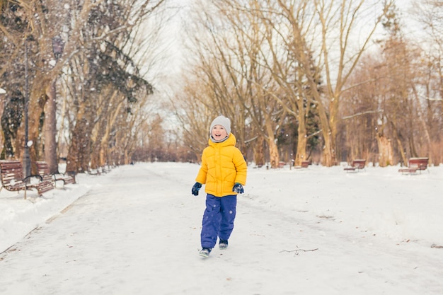 Menino em um passeio no parque com a família no inverno, se divertindo e curtindo a neve