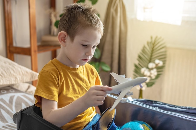 Menino em uma camiseta amarela está brincando com um avião de brinquedo indo em uma jornada em direção à aventura