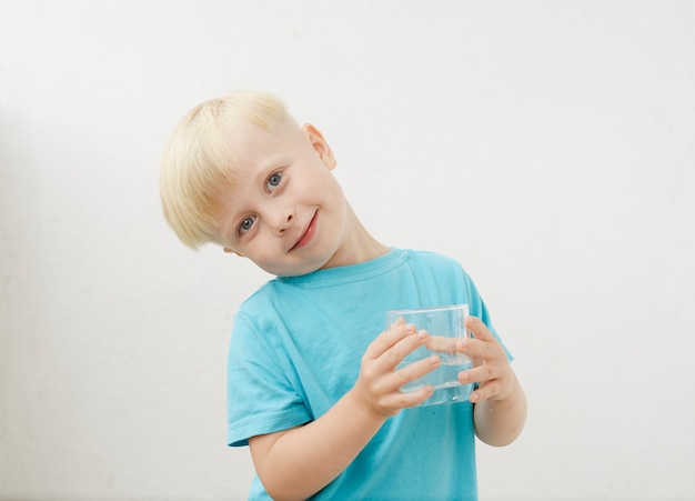 Menino em uma camiseta azul bebe água