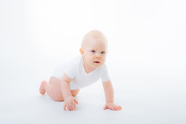 Menino em uma roupa branca rastejando em um fundo branco