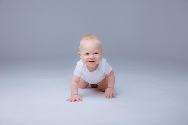 Menino em uma roupa branca rastejando em um fundo branco