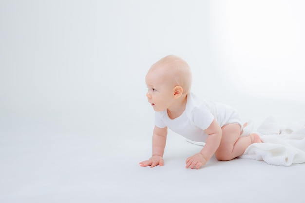 Menino em uma roupa branca rastejando em um fundo branco