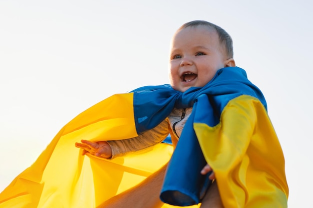 Menino embrulhado na bandeira amarela e azul da ucrânia no dia da independência ao ar livre