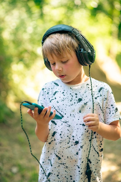Menino emocional de 9 anos na floresta com fones de ouvido ouvindo música