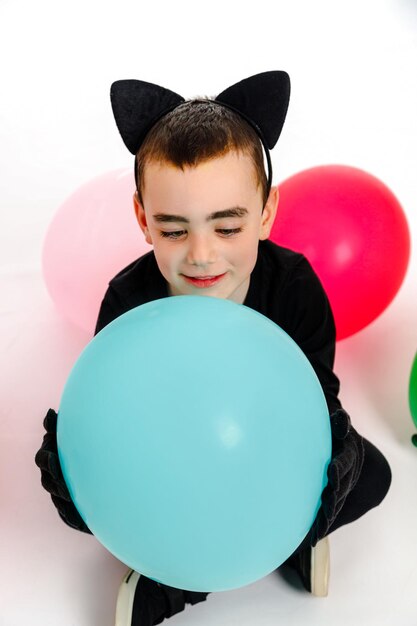 Menino emocional vestido como um gato preto com um balão azul Isolado Purim Halloween