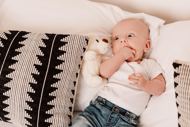 Menino engraçado bonito criança bebê deitado em almofadas de cama com brinquedo fofo. criança brincalhona