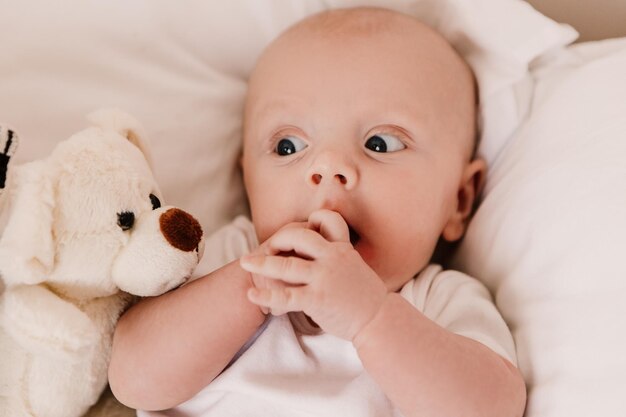 Menino engraçado bonito criança bebê deitado em almofadas de cama com brinquedo fofo. criança brincalhona