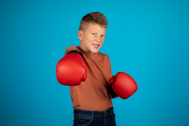 Menino engraçado usando luvas de boxe dando soco na câmera