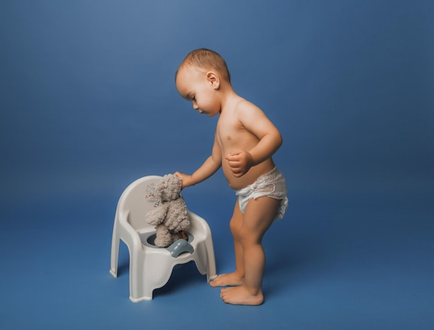 Menino ensina um brinquedo de pelúcia para o penico.