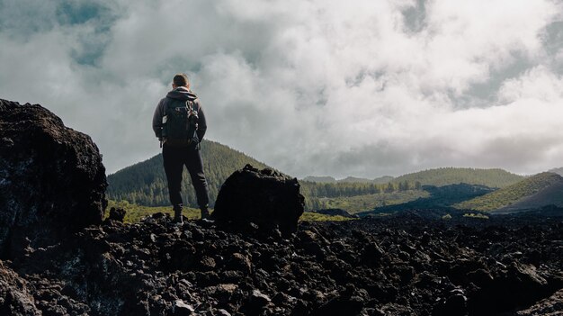 Foto menino escalando em uma rota de montanha com uma paisagem vulcânica ao fundo