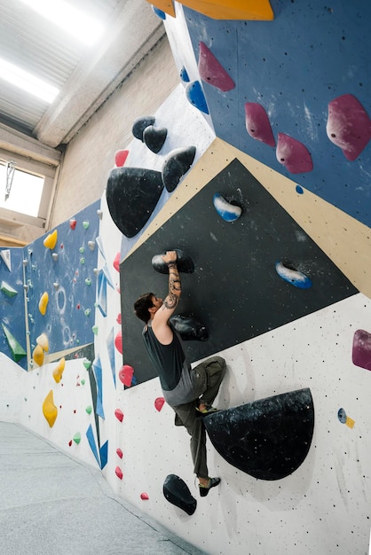 Menino escalando uma parede em uma parede de escalada interna