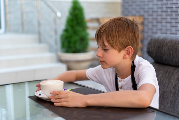 Menino está tomando café no café