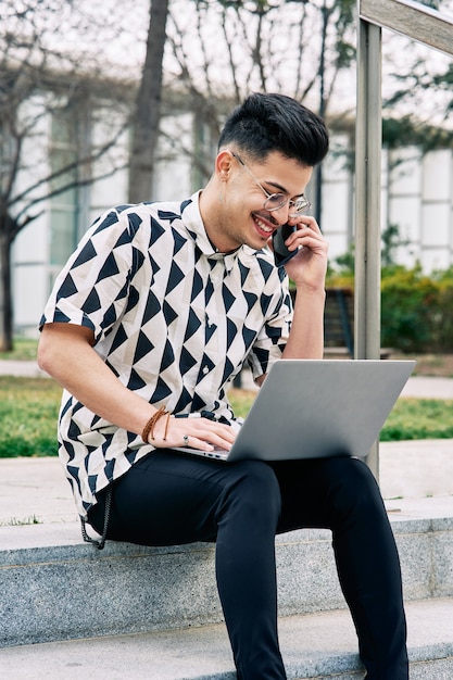 Foto menino estudando em um parque com um laptop e uma scooter