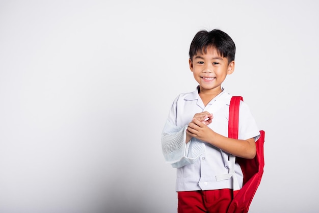 Menino estudante asiático vestindo uniforme tailandês de estudante acidente osso quebrado usando gesso de braço de tala