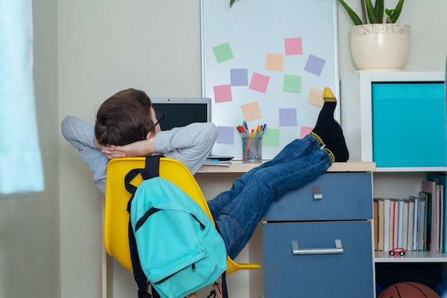 Menino estudante faz lição de casa em sentar em uma mesa em casa. De volta à escola. Ambiente de estudo em casa.