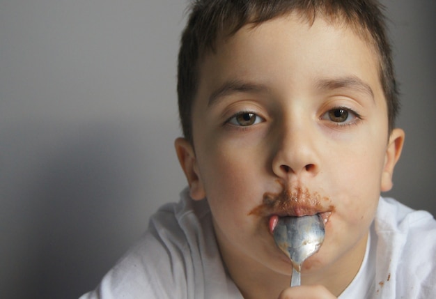 Menino europeu comendo chocolate Criança feliz e fofa coberta de chocolate