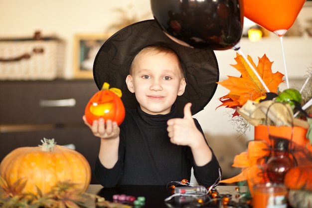 Menino fantasiado de bruxa no Halloween com abóbora