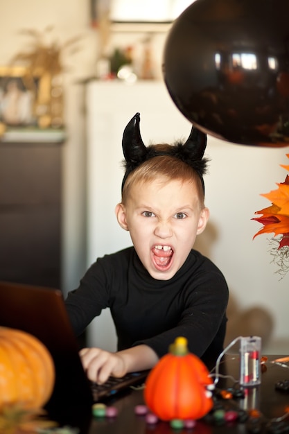 Menino fantasiado de bruxa para o Halloween usando um laptop