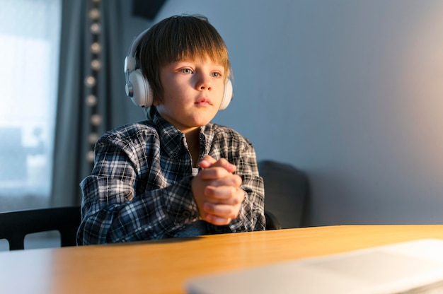 Menino fazendo cursos virtuais no laptop e orando